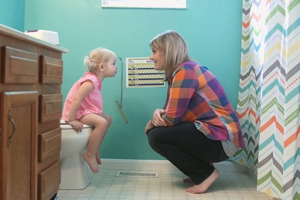 A woman and child in the bathroom on the toilet