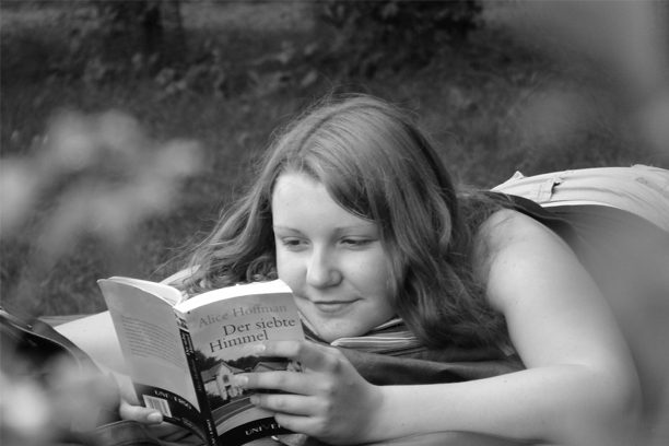A girl is reading a book outside