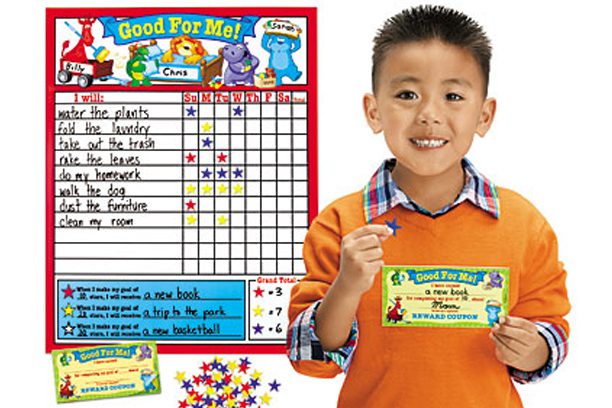 A boy holding up his reward card and a board.