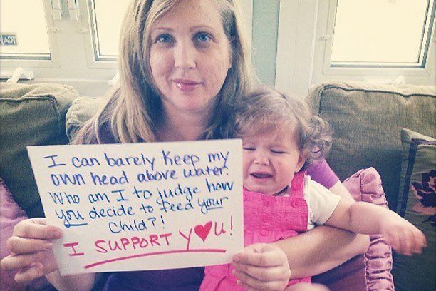 A woman holding a sign with a child in it.