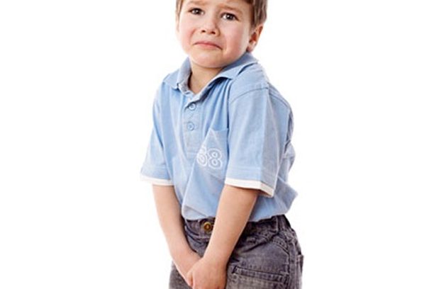 A little boy in blue shirt and jeans holding his hands on the hips.
