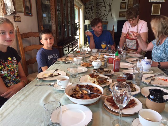 A family sitting at the table with plates of food.