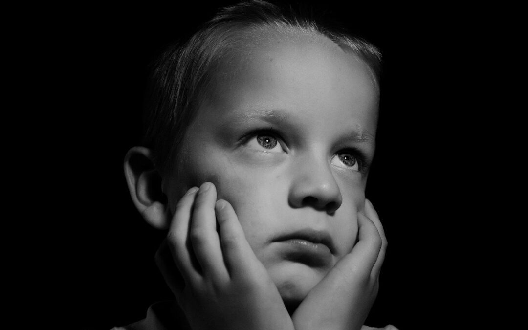 A young boy is looking up at the sky.